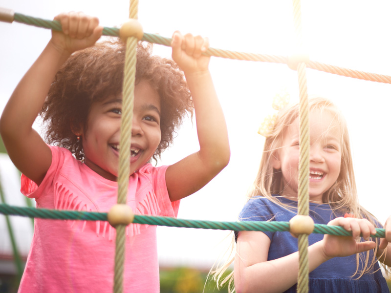 Two smiling girls on playground ropes